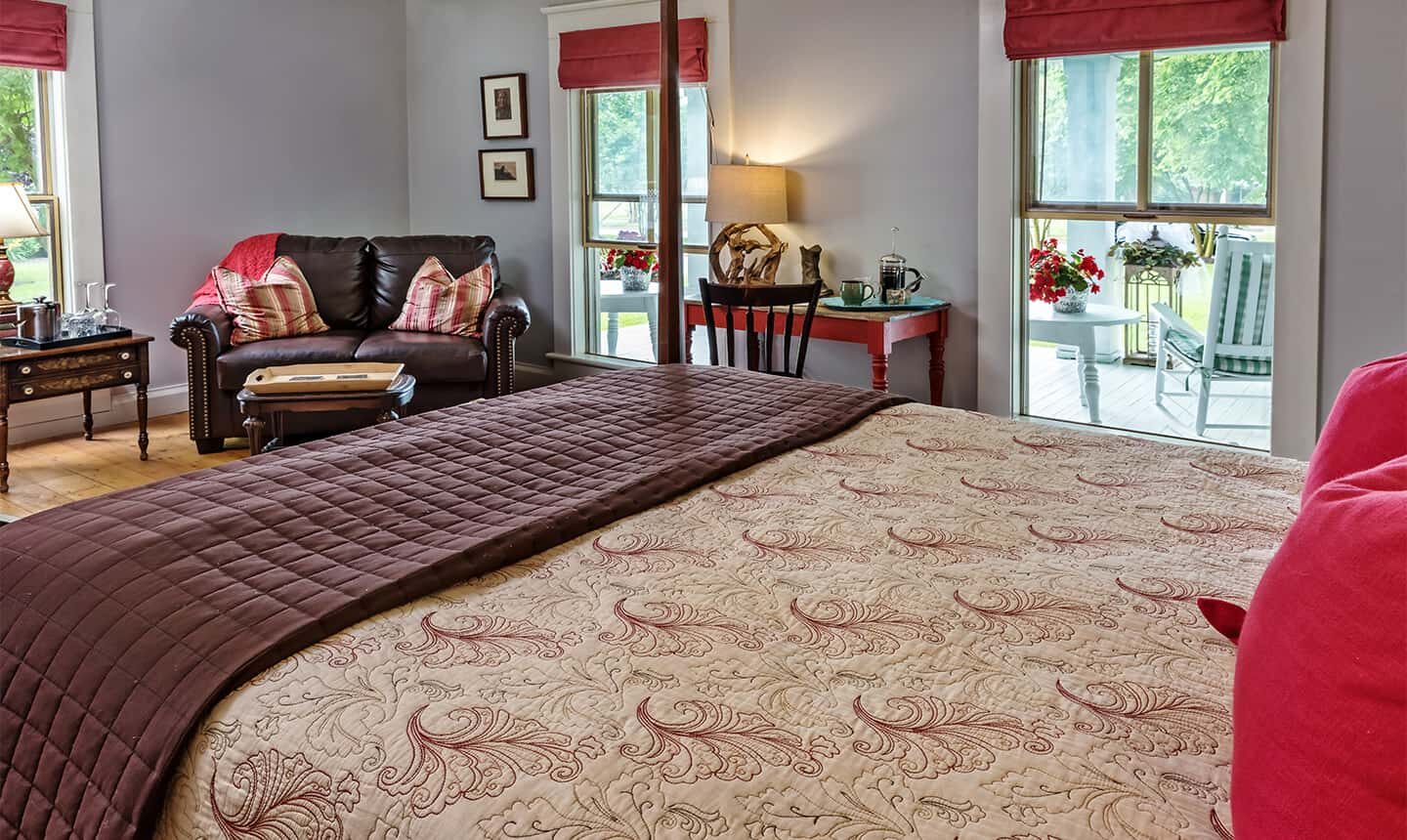 Bed and leather loveseat in Deluxe Queen Room of the Pack House