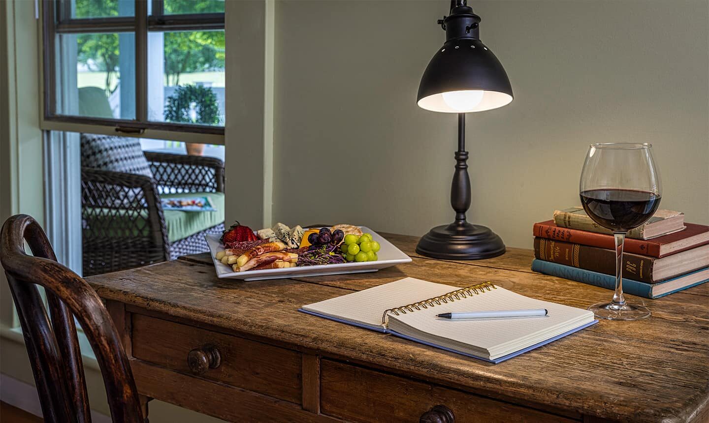 Desk with notebook, cheese, and fruits and glass of wine