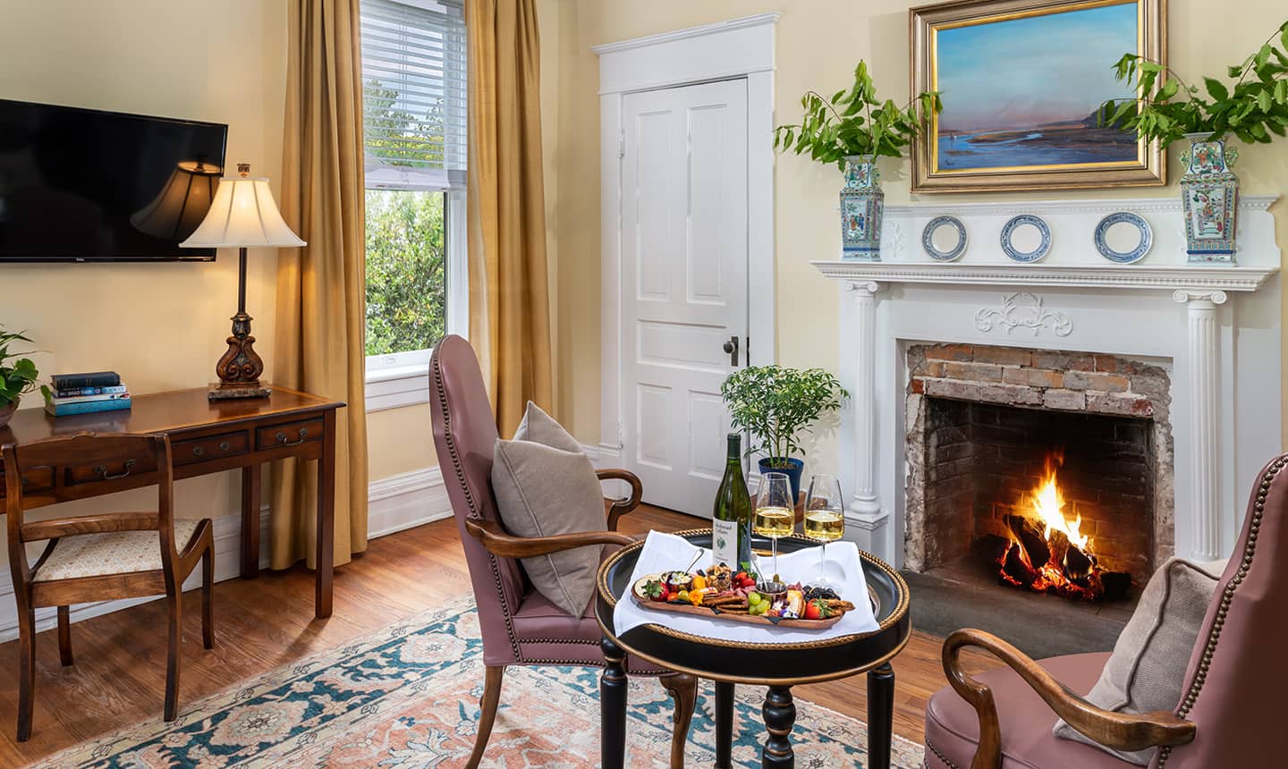 Fireplace and chairs in Daniel Earle Suite with wine