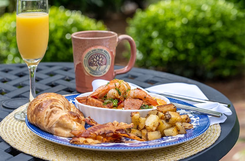 Breakfast plate of food with coffee cup and orange juice in the background