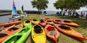 A group of kayaks on the grass in next to the Edenton Bay
