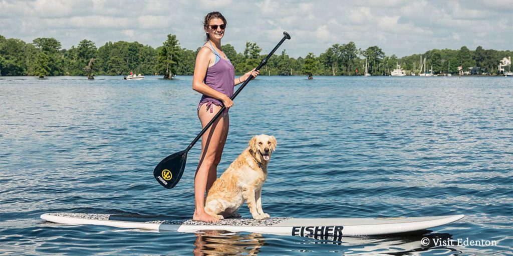 A woman paddleboarding with her dog in the Albemarle Sound in Edenton, NC