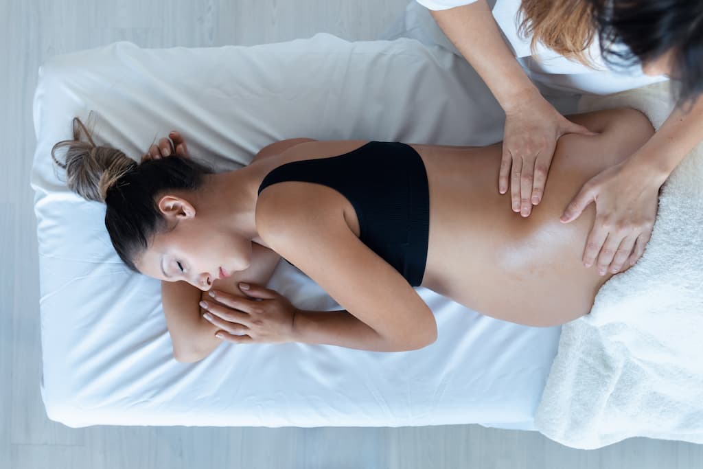 A pregnant woman lying on her side getting a massage during her babymoon getaway at our North Carolina bed and breakfast.