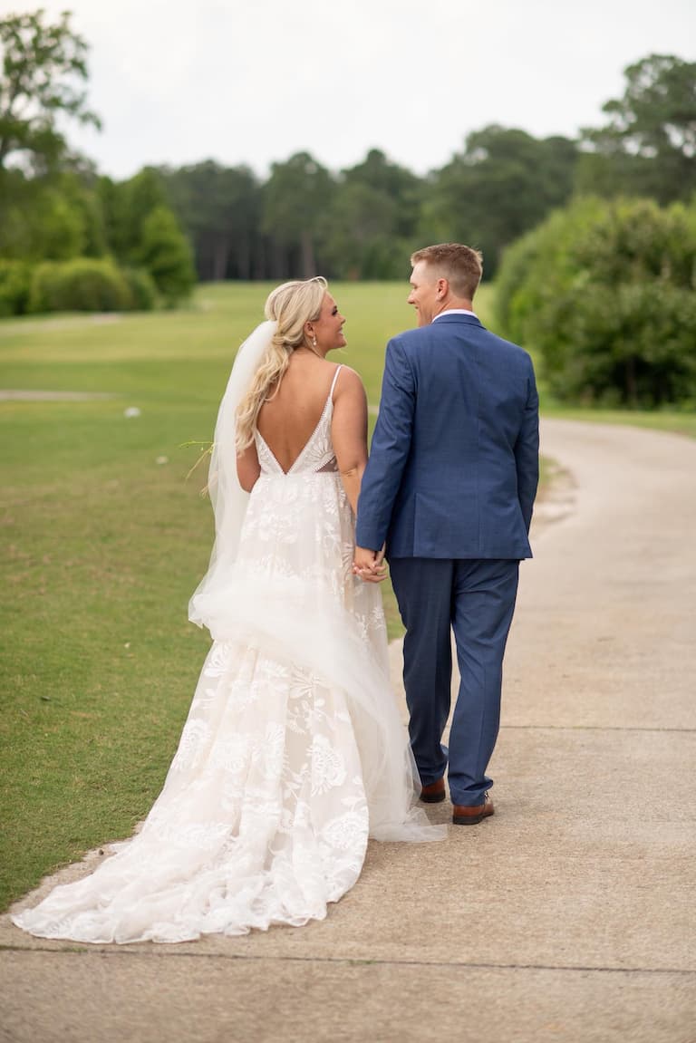 A bride and groom walking at the Links at Mulberry Hill, an outdoor NC wedding venue