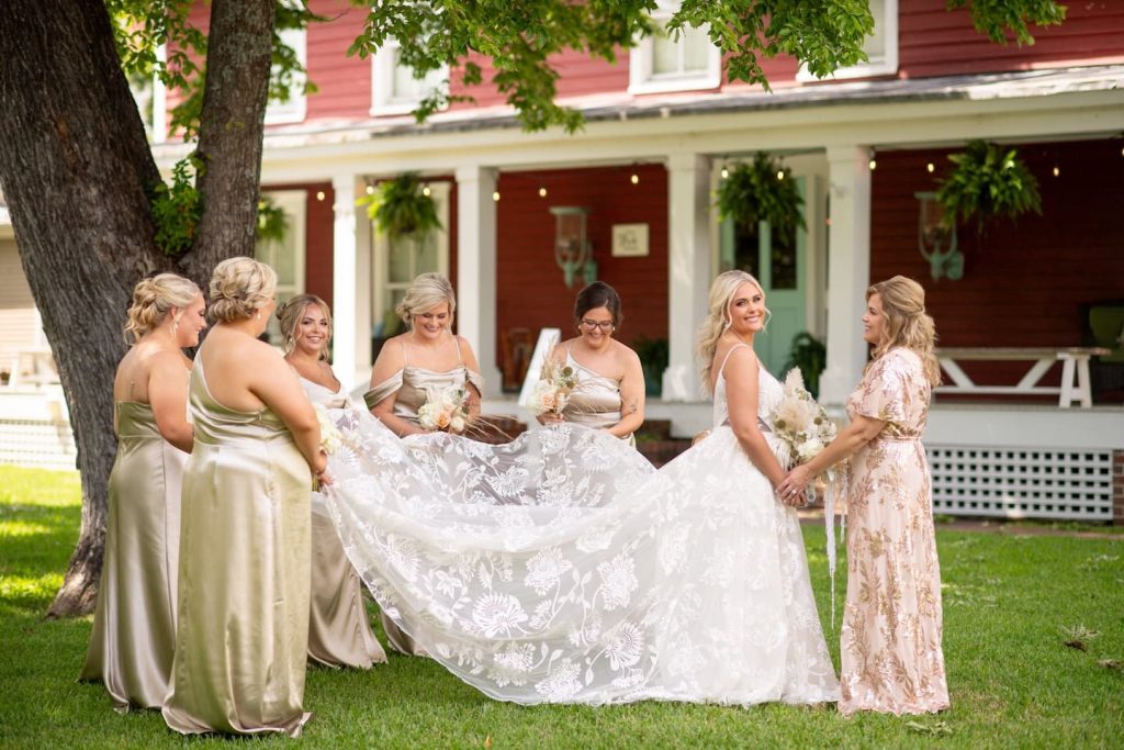 A group of bridesmaids holding the train of a bride's dress in front of the Inner Banks Inn in Edenton, NC