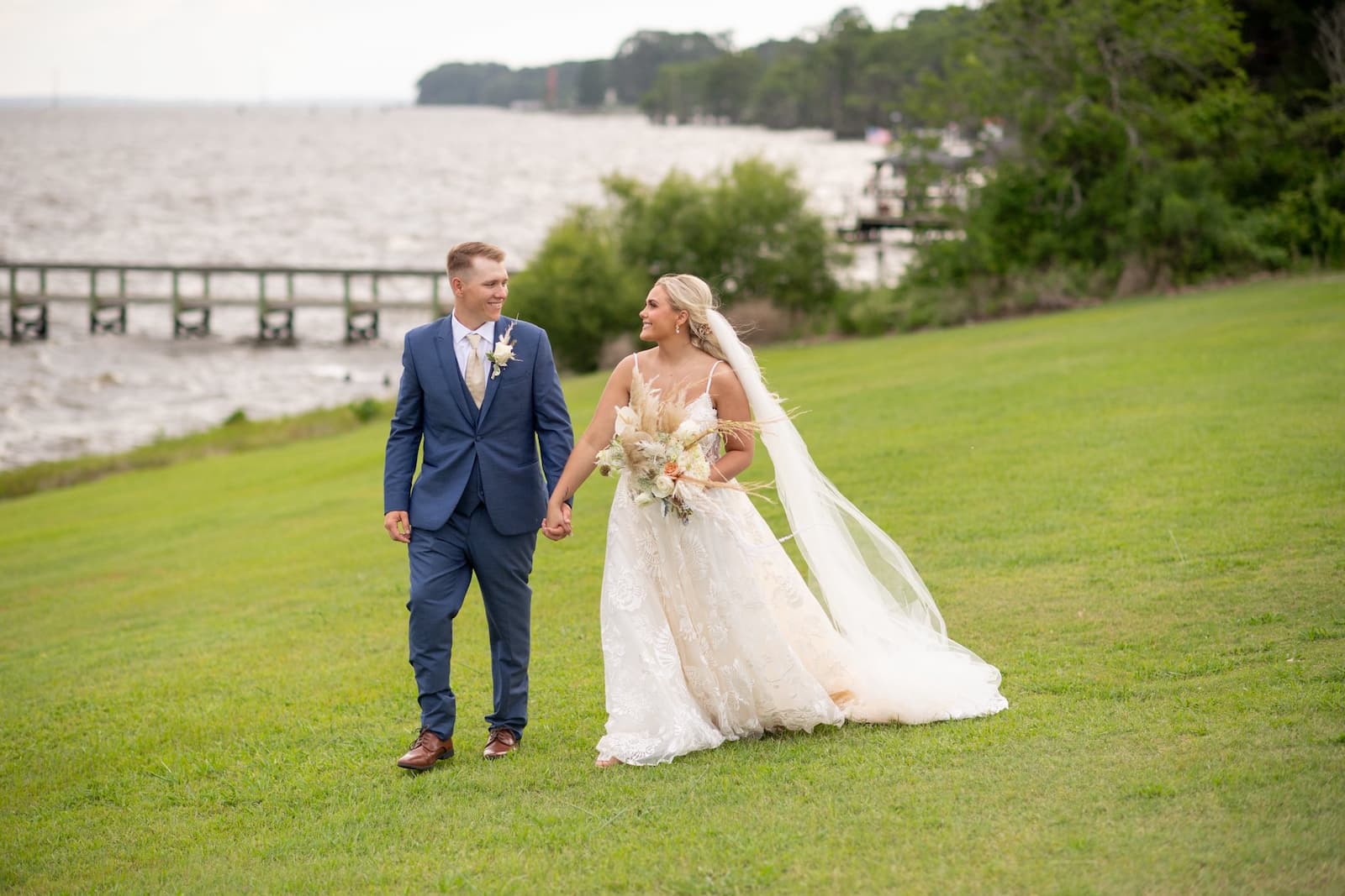 A bride and groom walking along the Albemarle Sound at the Links at Mulberry Hill, an outdoor NC wedding venue